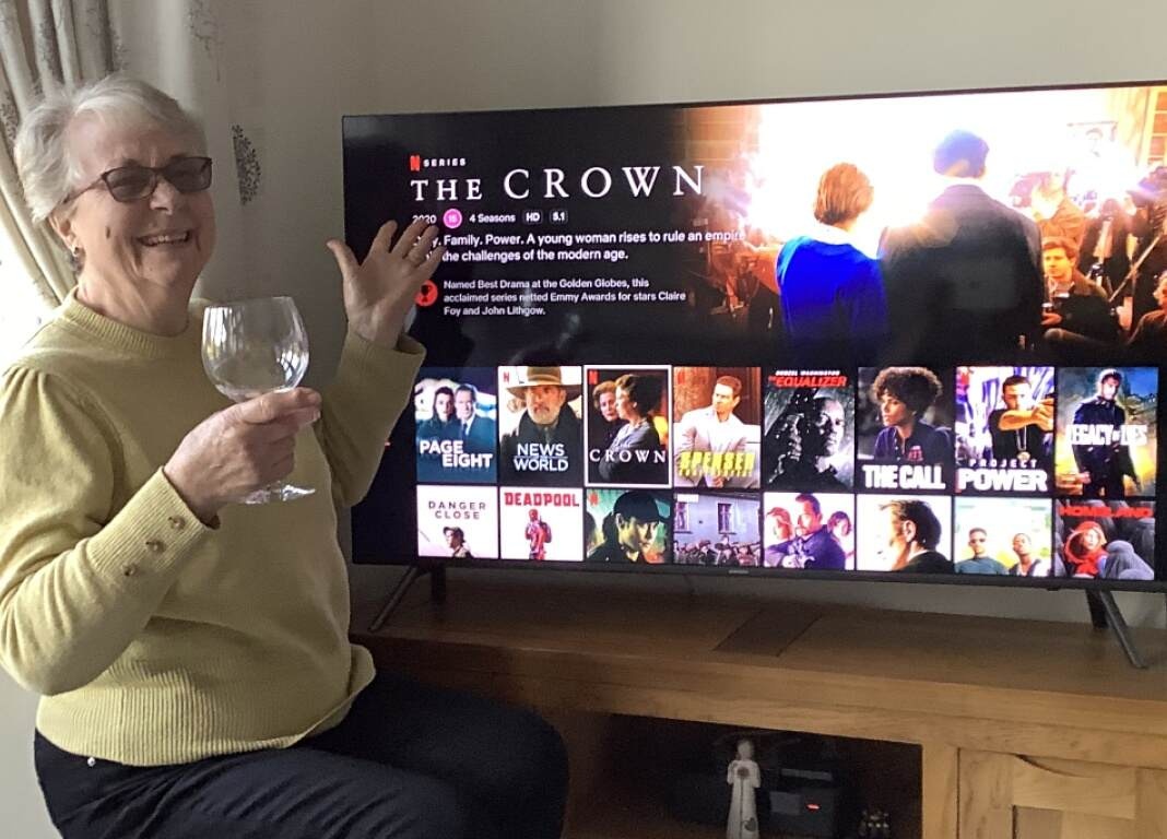 Happy woman with a drink and a tv in background
